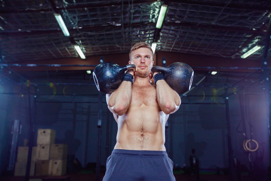 Man holding two kettlebells in the "rack" position.
